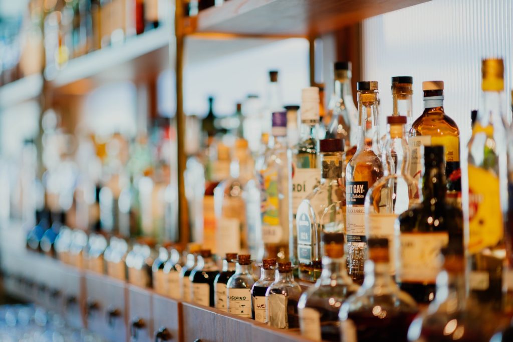 Rows of liquor bottles arranged on a bar's open shelving.