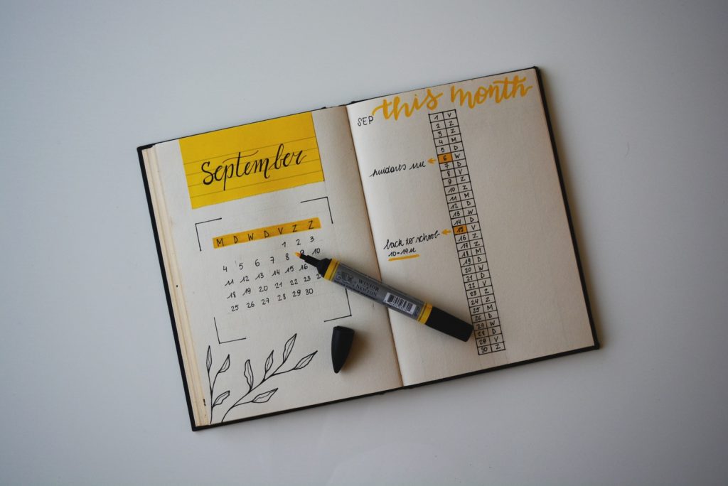 A bullet journal with yellow accents showing a calendar for the month of September.