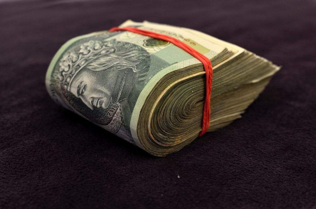 A wad of cash bound with a red rubber band.