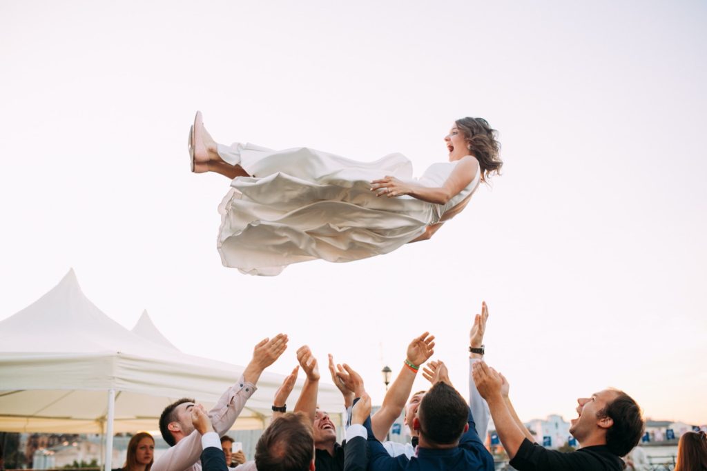 A new bride gets tossed into the air by several of her reception guests.