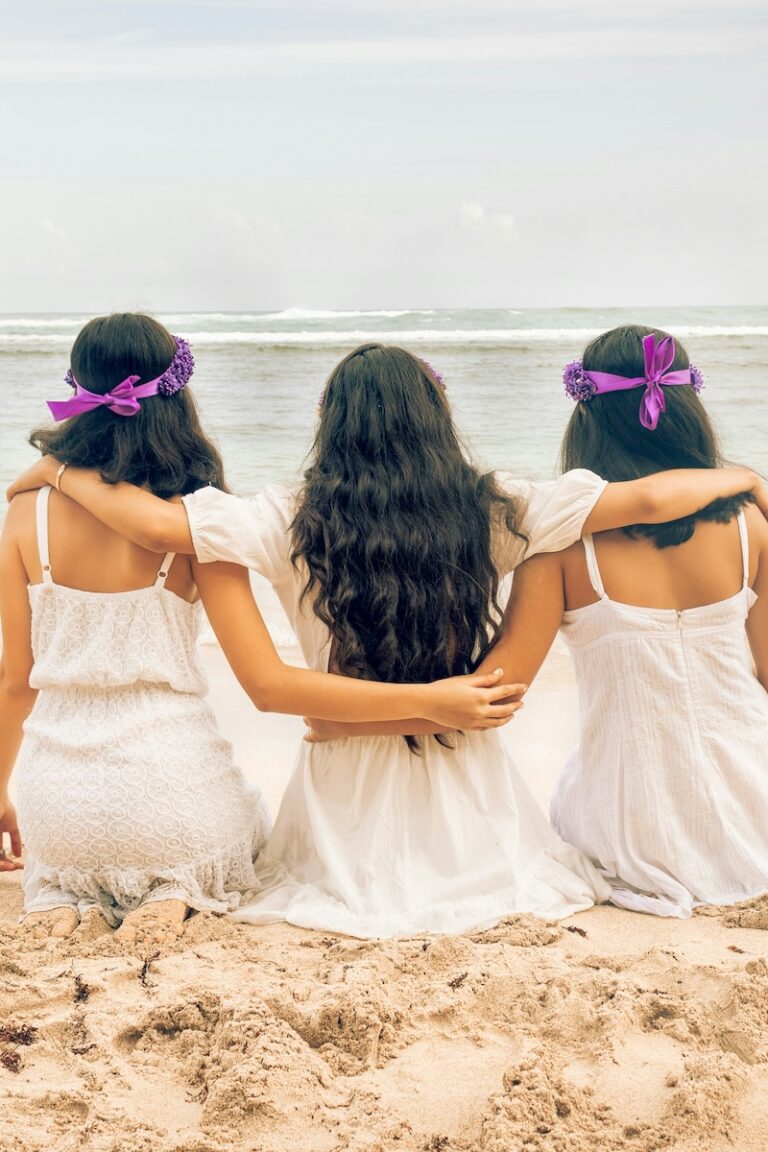 bride with maid of honor and bridesmaid on a beach with their backs turned to camera