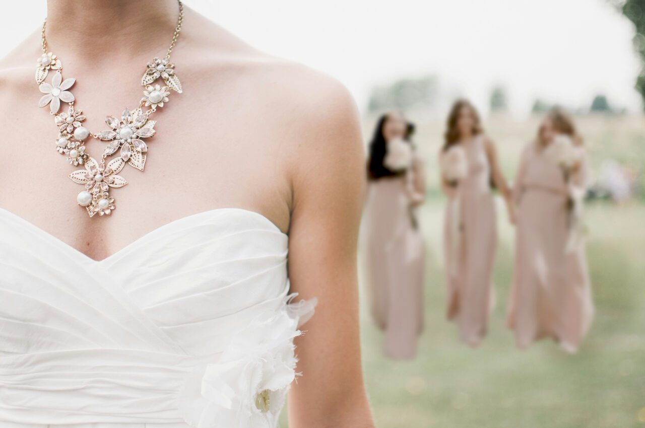 bride in foreground cropped at the face with happy bridesmaids behind her