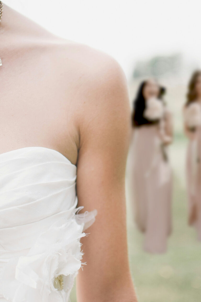 bride in foreground cropped at the face with happy bridesmaids behind her