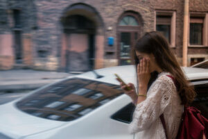 stressed harried young woman in white lace looking at her phone outdoors with her hand by her face