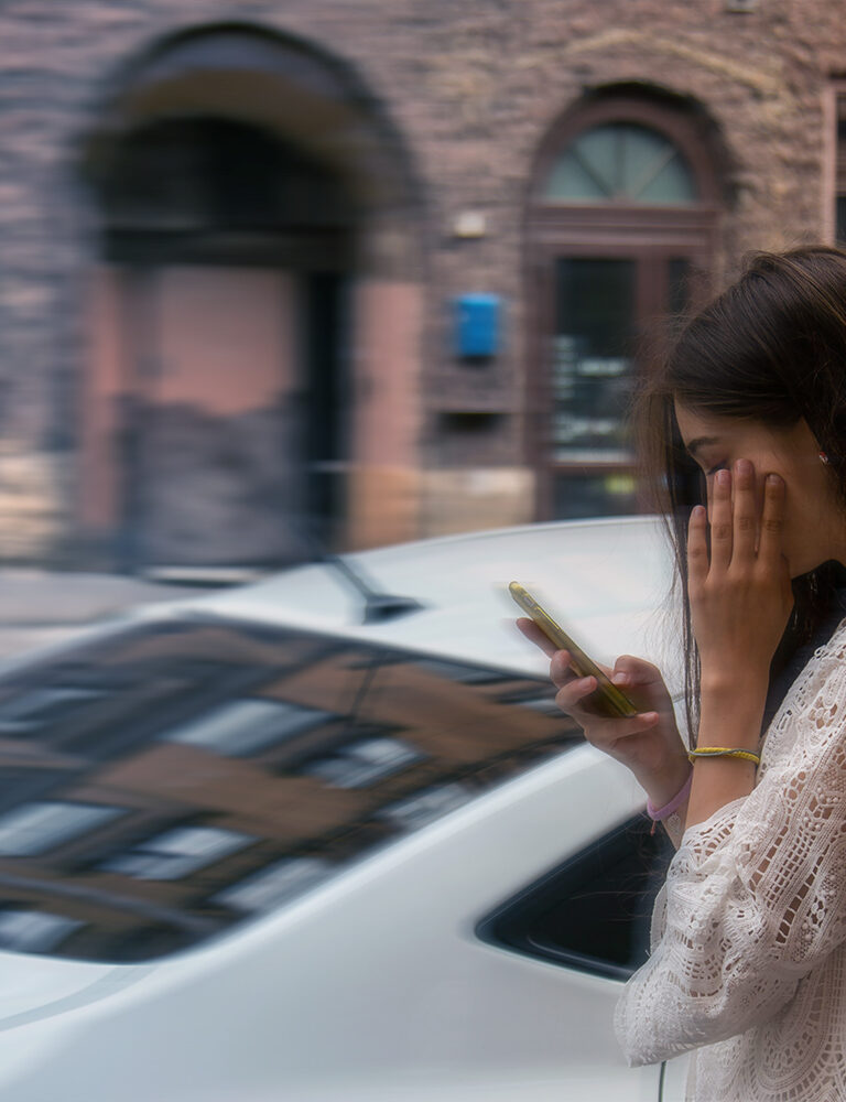 stressed harried young woman in white lace looking at her phone outdoors with her hand by her face