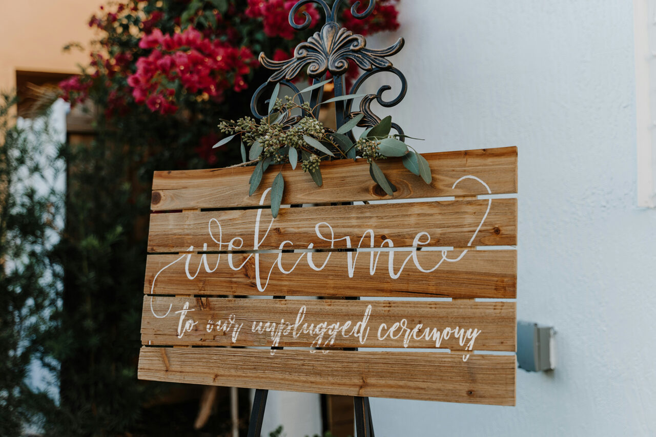 rustic wood handpainted wedding sign reading welcome to our unplugged ceremony