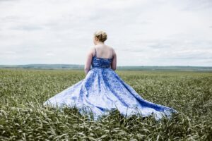 Blonde curvy bridesmaid in a formal blue dress outdoors