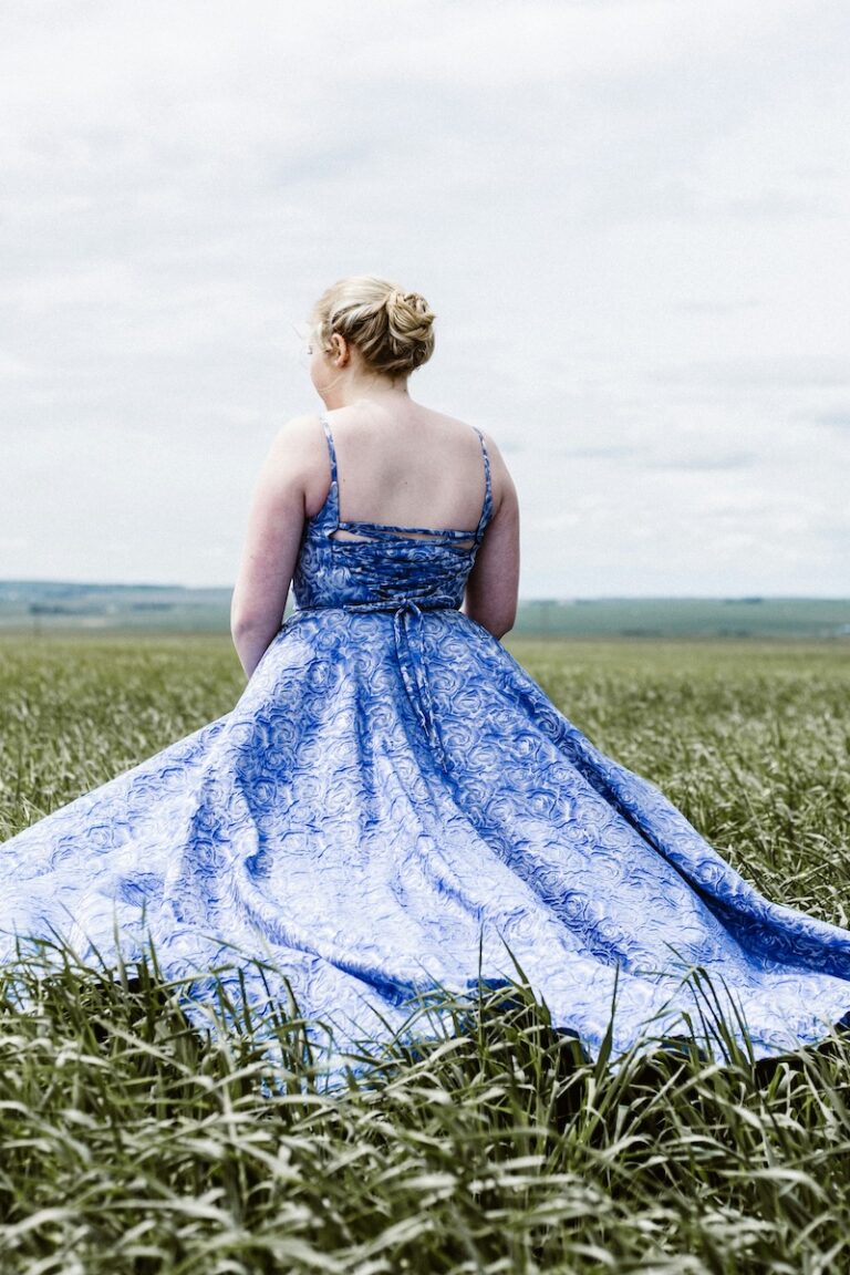 Blonde curvy bridesmaid in a formal blue dress outdoors