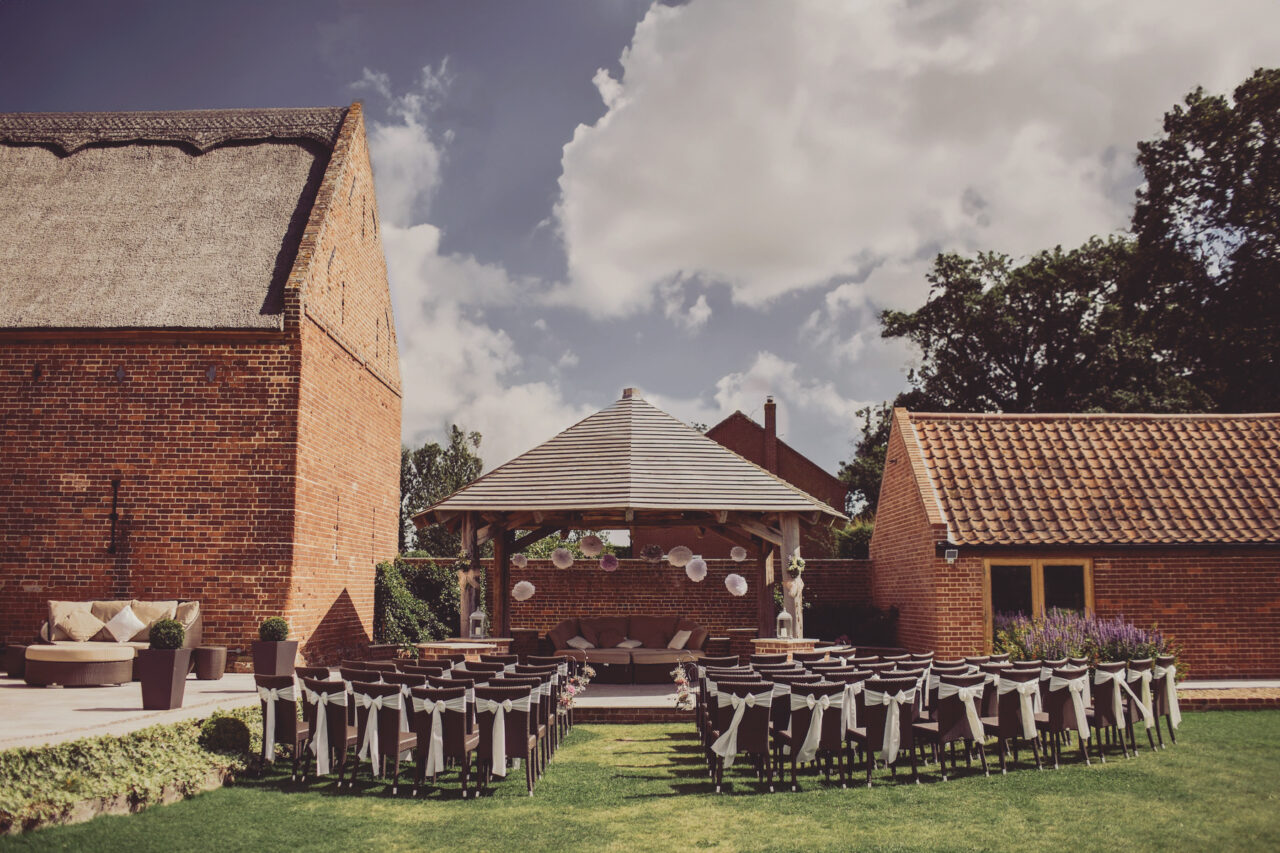 outdoor wedding ceremony site with a gazebo altar and brick buildings