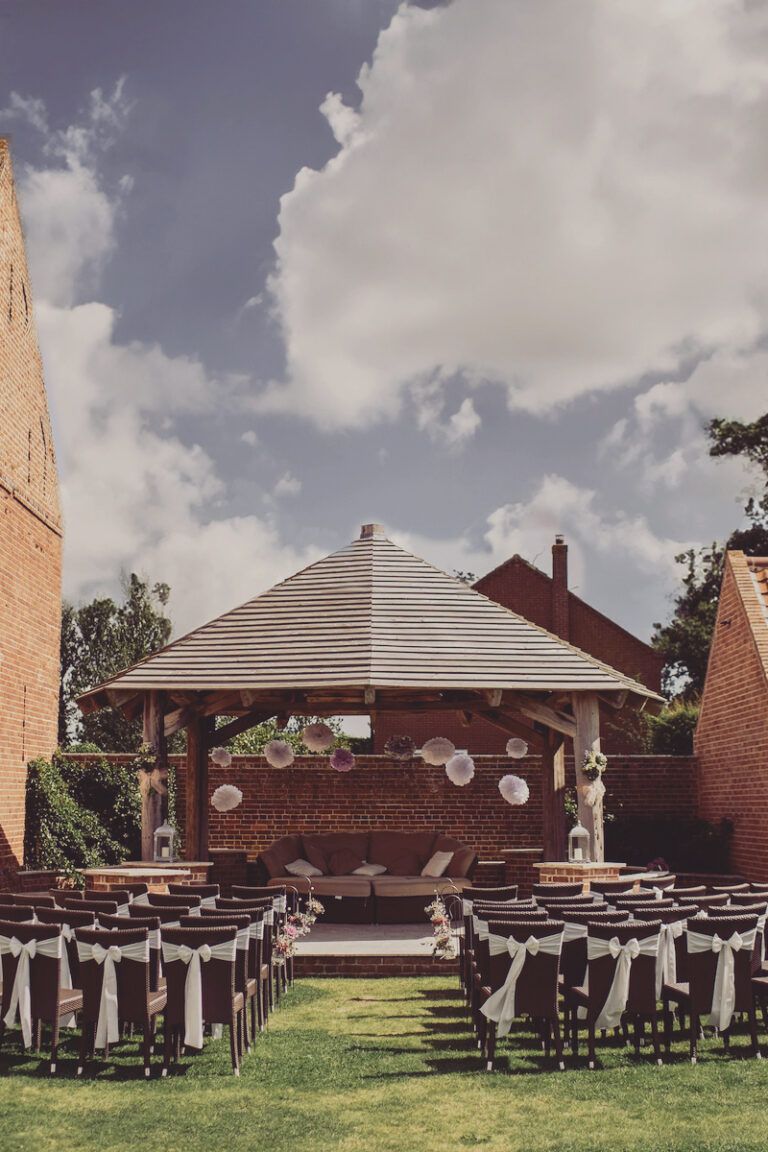 outdoor wedding ceremony site with a gazebo altar and brick buildings