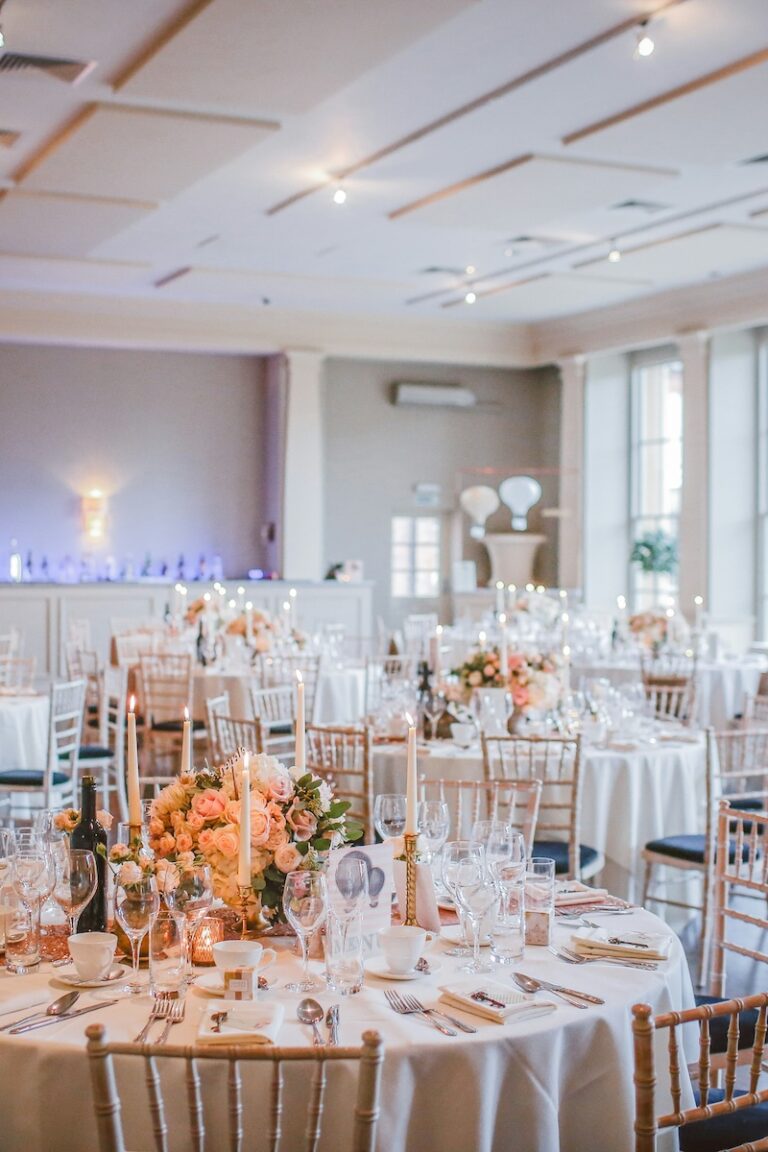 beautiful reception hall decked out with flowers and pink tableclothes, and gold cane chairs, ready for guests