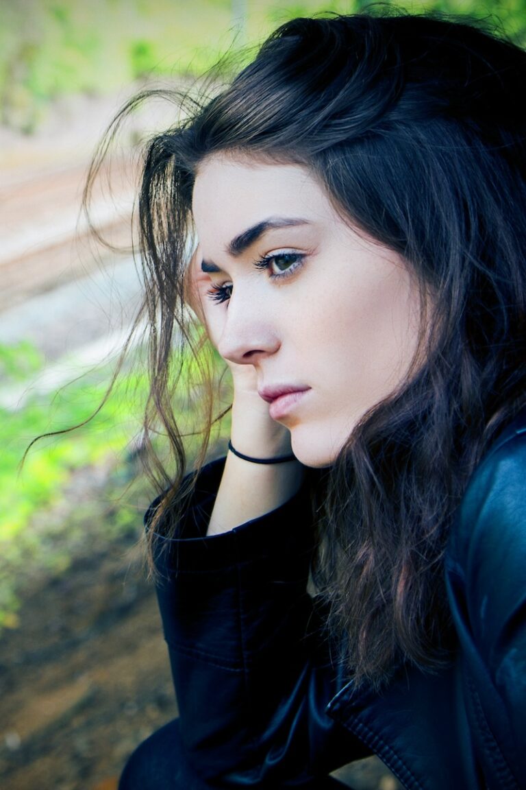 Thoughtful brunette woman looking at railroad tracks from window